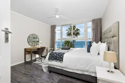 a bedroom with a bed and a desk and a window at ZenDen Destinations' Tidal Tranquillity in Cape Town
