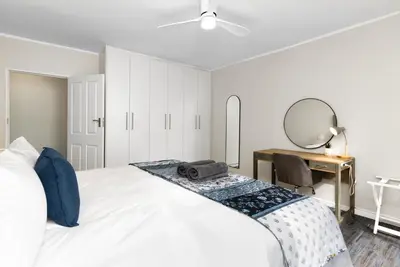 a bedroom with a bed with a desk and a mirror at ZenDen Destinations' Tidal Tranquillity in Cape Town