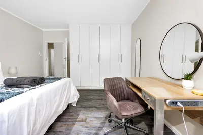 a bedroom with a bed and a desk and a mirror at ZenDen Destinations' Tidal Tranquillity in Cape Town