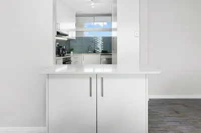 a white kitchen with white cabinets in a room at ZenDen Destinations' Tidal Tranquillity in Cape Town