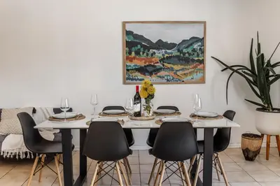 a dining room table with chairs and a painting on the wall at Silvertree Collective Spacious Central Apartment in Stellenbosch