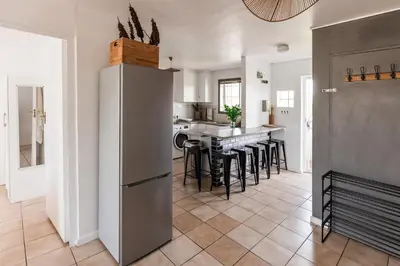 a kitchen with a refrigerator and a table with stools at Silvertree Collective Spacious Central Apartment in Stellenbosch