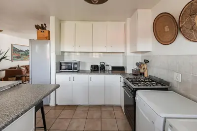 a kitchen with white cabinets and a stove top oven at Silvertree Collective Spacious Central Apartment in Stellenbosch
