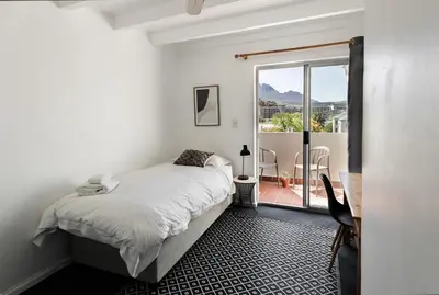a white bedroom with a bed and a balcony at Silvertree Collective Spacious Central Apartment in Stellenbosch