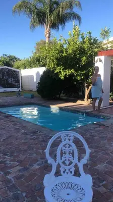 a woman standing in front of a swimming pool at Gatsby Suite, with pool in quiet area, close to town in Stellenbosch