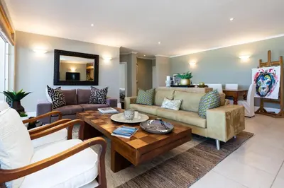 a living room with a couch and a table at Lagoon Beach Penthouse in Cape Town