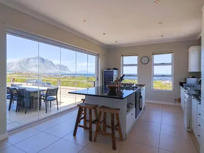 a kitchen with a table and chairs and a large window at Penguin View in Bettyʼs Bay