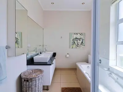 a bathroom with a sink and a toilet and a tub at Penguin View in Bettyʼs Bay