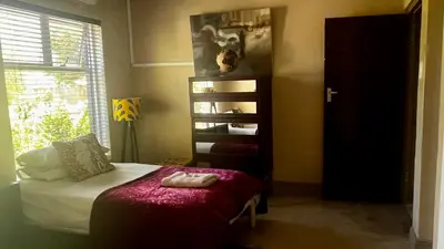 a bedroom with a bed and a book shelf at Listening Wind Self-Catering accommodation in Bettyʼs Bay