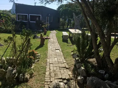 a garden with a brick path in front of a house at Listening Wind Self-Catering accommodation in Bettyʼs Bay