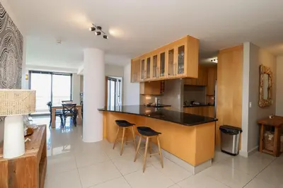 a kitchen with a counter and stools in a room at 1402 Hibernian Towers Luxury Self Catering Apartment Strand Western Cape South Africa in Cape Town
