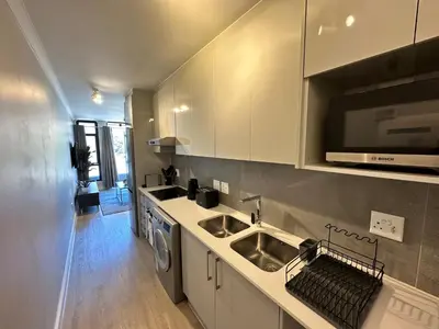 a kitchen with white cabinets and a sink at The Westwood Deluxe Studio in Cape Town