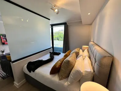 a living room with a couch and a large screen at The Westwood Deluxe Studio in Cape Town