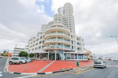 a large building with cars parked in front of it at 1401 Hibernian Towers Luxury Self Catering Apartment Strand Western Cape South Africa in Cape Town