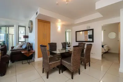 a dining room with a table and chairs and a couch at 1401 Hibernian Towers Luxury Self Catering Apartment Strand Western Cape South Africa in Cape Town