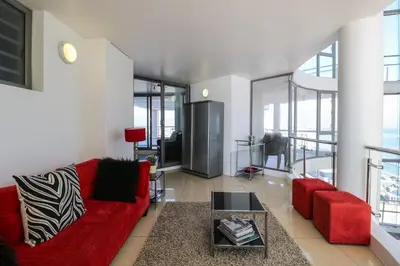 a living room with a red couch and a table at 1401 Hibernian Towers Luxury Self Catering Apartment Strand Western Cape South Africa in Cape Town