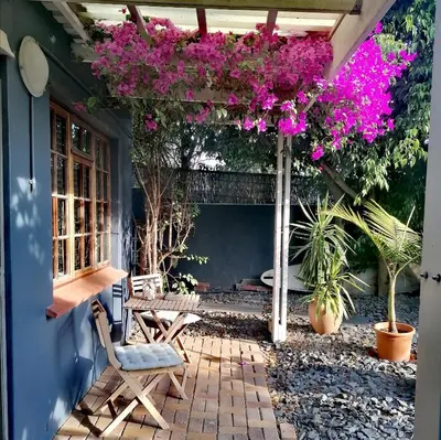 a patio with a table and a bunch of flowers at Aloha Lodge in Cape Town