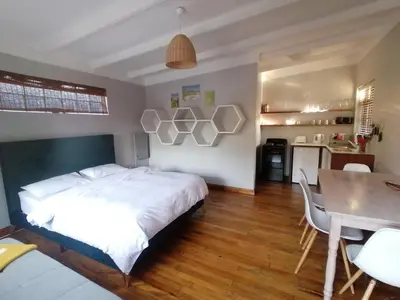 a bedroom with a bed and a table and a dining room at Aloha Lodge in Cape Town