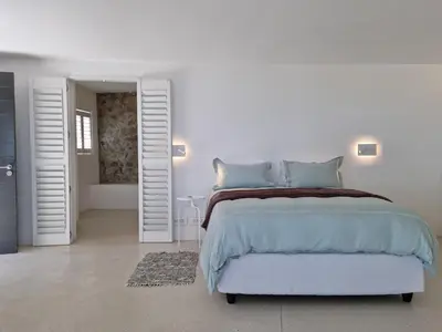 a white bedroom with a large bed and a bathroom at 'Kaya Moya' - Luxury Suite for 2 with Ocean Views in Gordonʼs Bay