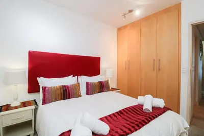 a bedroom with a large white bed with a red headboard at 506 Hibernian Towers Luxury Self Catering Apartment Strand Cape Town South Africa in Cape Town