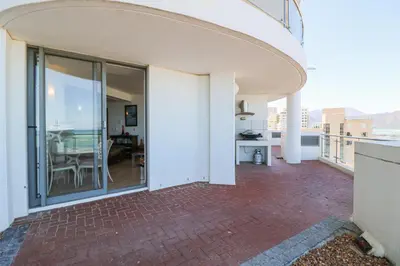 a balcony with sliding glass doors and a dining room at 506 Hibernian Towers Luxury Self Catering Apartment Strand Cape Town South Africa in Cape Town