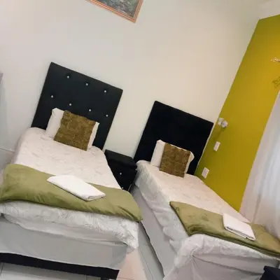 two twin beds in a room with green and white at Sunshine Guest House in Cape Town