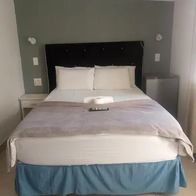 a bedroom with a large bed with a remote control on it at Sunshine Guest House in Cape Town