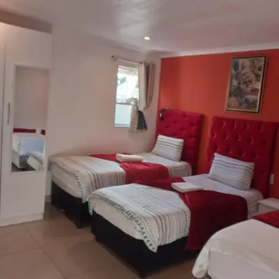 two beds in a room with red walls at Sunshine Guest House in Cape Town