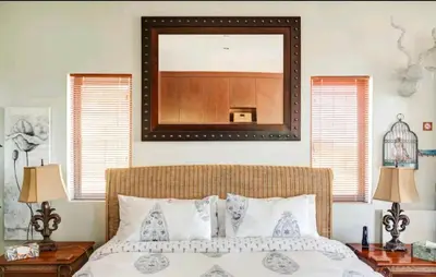 a bedroom with a large mirror above a bed at Devon View Olive Farm in Stellenbosch