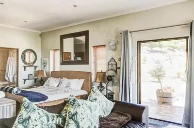 a bedroom with a bed and a couch and a window at Devon View Olive Farm in Stellenbosch