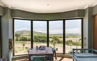 a living room with a table and a large window at Devon View Olive Farm in Stellenbosch