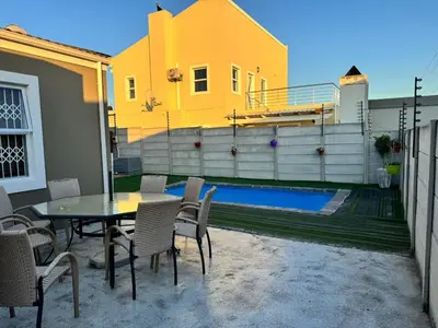 a patio with a table and chairs and a pool at Blue Lily Haven Cape Town Self Catering Home in Cape Town