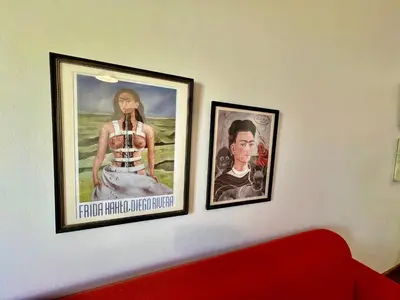 two posters on a wall next to a red couch at 2 Bedroom Apartment On Dorp St - Prime Location in Stellenbosch