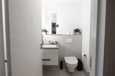 a white bathroom with a toilet and a sink at Bridgewater Studio Apartment in Century City