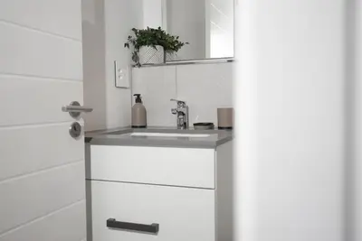 a white bathroom with a sink and a mirror at Bridgewater Studio Apartment in Century City