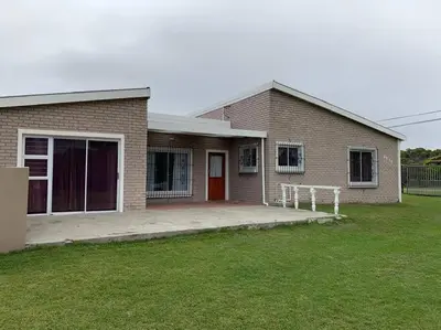a brick house with a red door and a yard at Silver’s Rest Beach House in Clareport