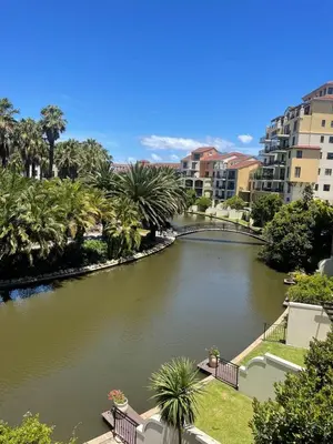 a river in a city with palm trees and buildings at 204 Island Club Luxury Apartment - Cape Town in Cape Town