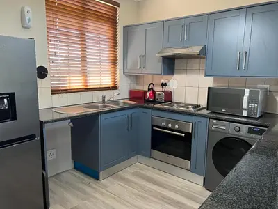 a kitchen with blue cabinets and a sink and a microwave at 204 Island Club Luxury Apartment - Cape Town in Cape Town