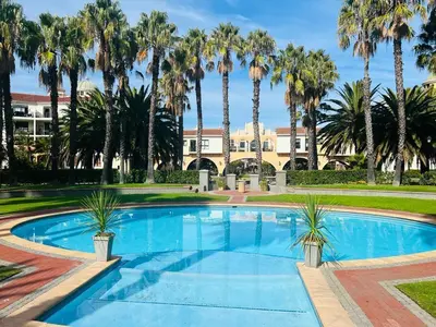 a pool with palm trees in front of a building at 204 Island Club Luxury Apartment - Cape Town in Cape Town