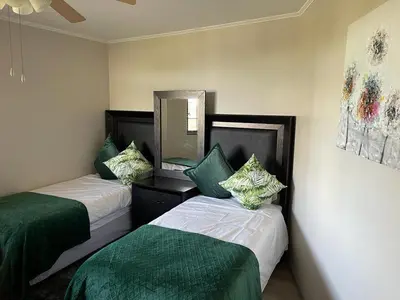 two beds in a room with green and white at 204 Island Club Luxury Apartment - Cape Town in Cape Town