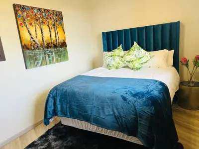 a bed with a blue headboard in a room at 204 Island Club Luxury Apartment - Cape Town in Cape Town