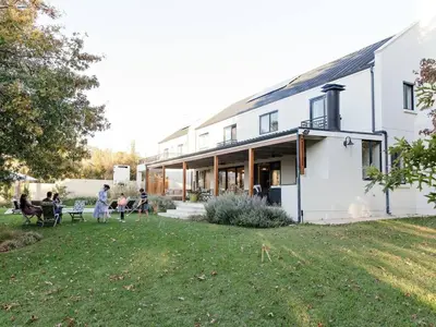 a white house with people sitting in a yard at Yonder Hill Accommodation in Raithby