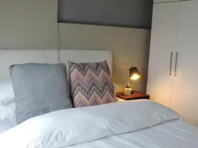 a bed with a pillow and a lamp on a table at Central Retreat Cozy Apartment Near Attractions in Cape Town