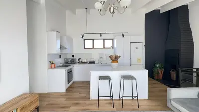 a white kitchen with a counter and two stools at Central Retreat Cozy Apartment Near Attractions in Cape Town