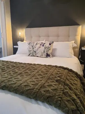 a bedroom with a large bed with white sheets and pillows at Helpmekaar in Wellington