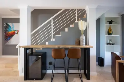 a dining room with a table and two stools at Luxury Lodge 5F, Pearl Valley Golf Estate in Paarl