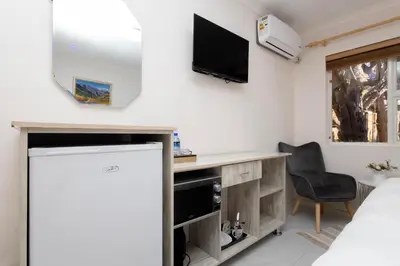 a room with a desk and a tv on the wall at Serena inn Room 1 in Cape Town