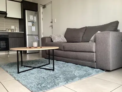 a living room with a couch and a table at Smartstay Apartments The Sandown in Cape Town
