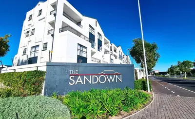 a sign in front of a white building at Smartstay Apartments The Sandown in Cape Town