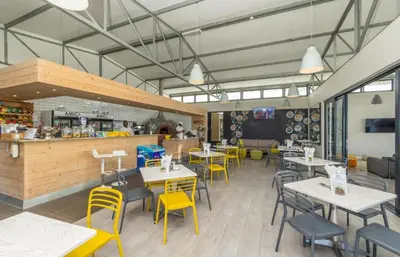 a restaurant with tables and yellow chairs and a counter at Smartstay Apartments The Sandown in Cape Town